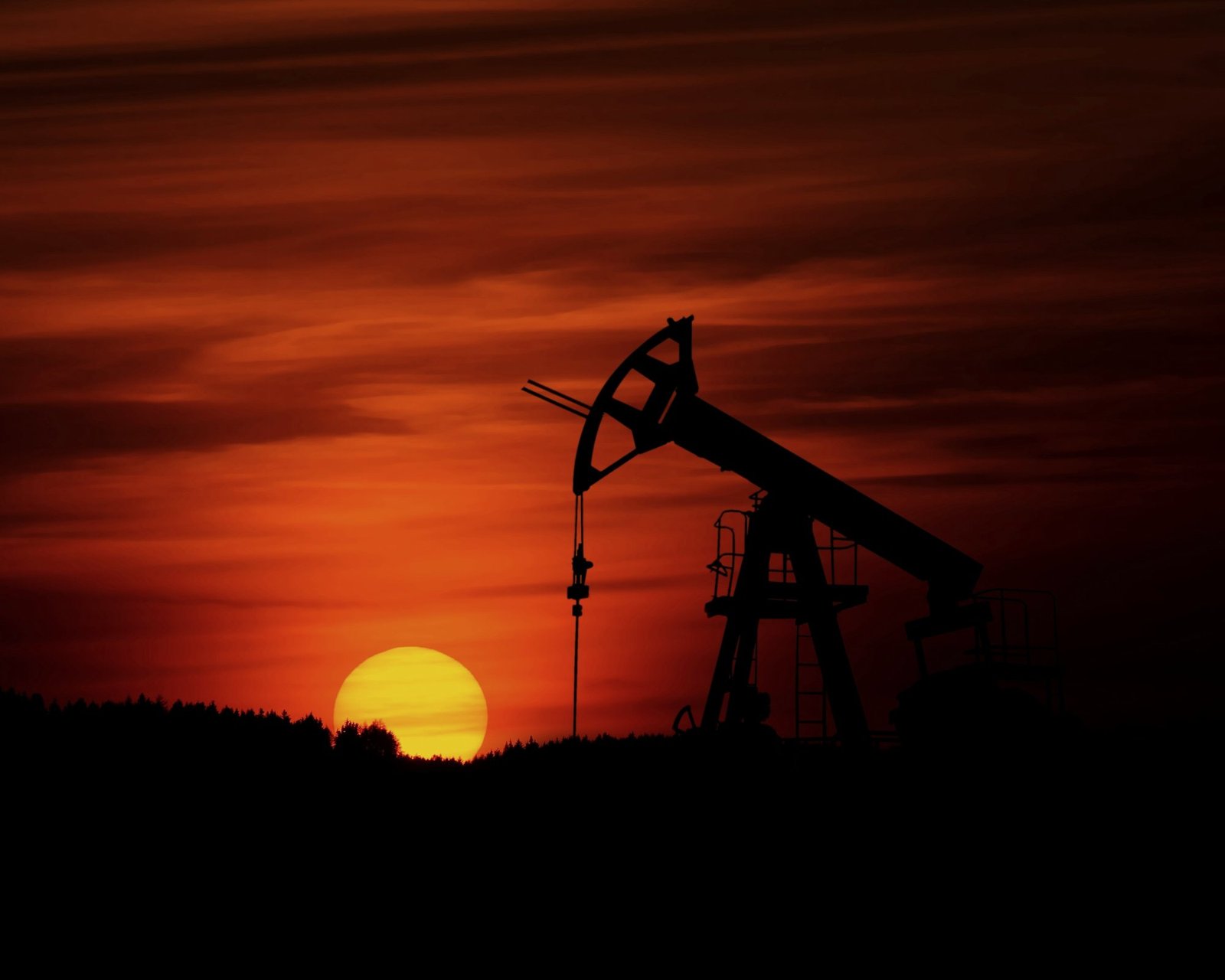 A pumpjack in silhouette against a sunset