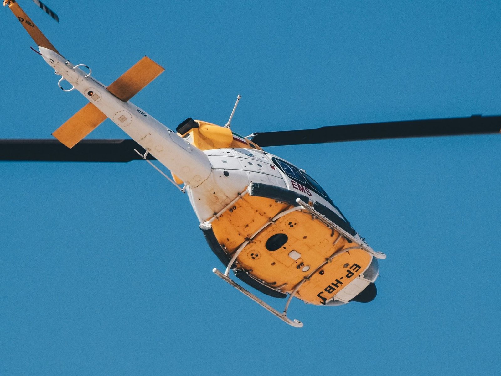 An air ambulance helicopter banking against a clear blue sky